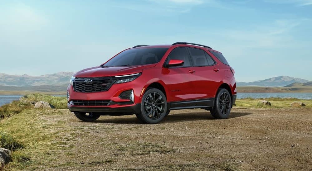 A red 2024 Chevy Equinox RS is shown pared near a lake after leaving a Chevy dealer.