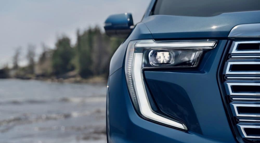 A close-up on the headlight of a blue 2024 GMC Acadia Denali is shown.