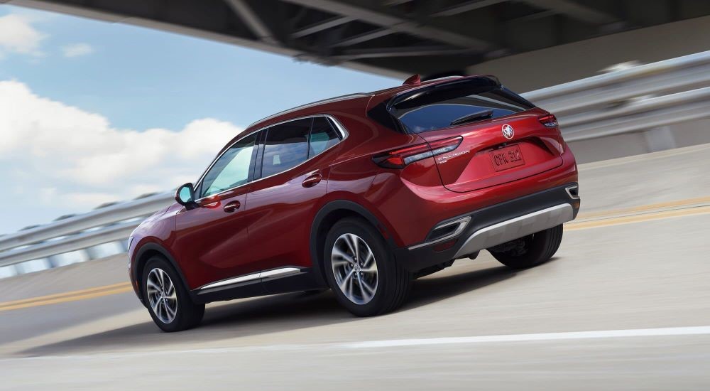 A red 2023 Buick Envision driving beneath a bridge.