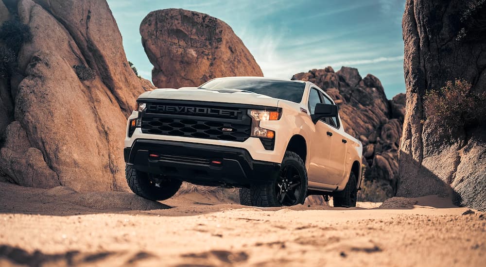 A white 2024 Chevy Silverado Z71 driving up a sandy hill.
