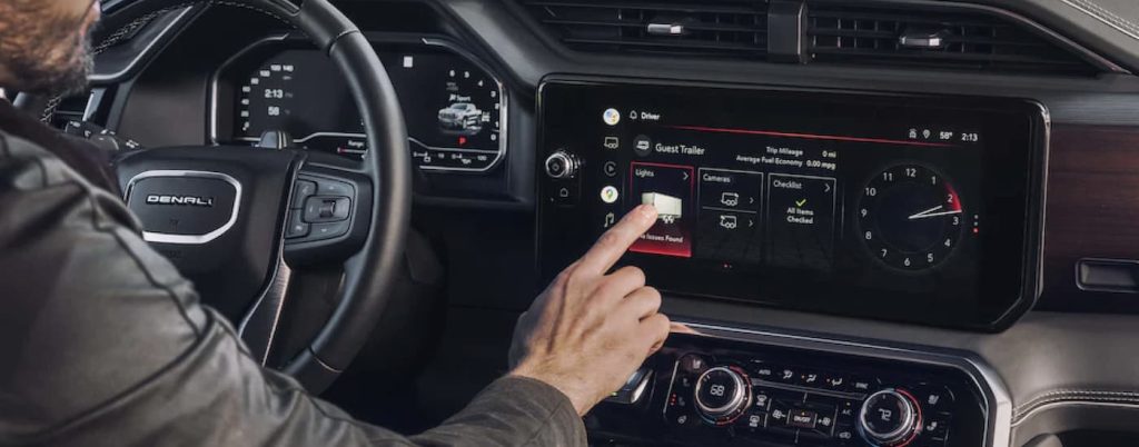 A man interacting with the dashboard in the black interior of a 2023 GMC Sierra 1500.