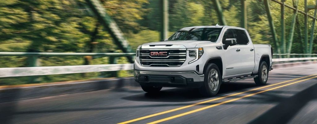 A white 2022 GMC Sierra 1500 driving over a bridge from a used GMC dealer.