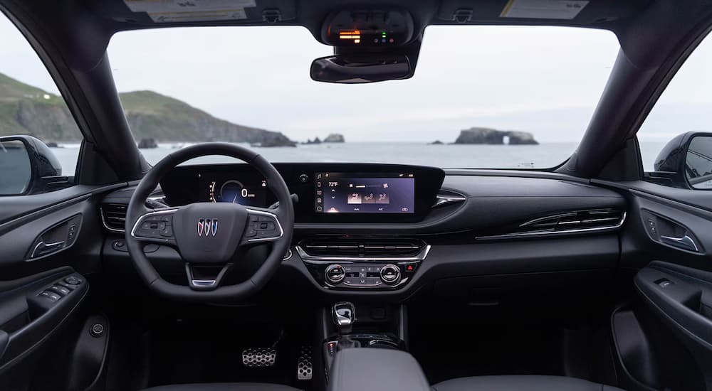 The black interior cabin, steering wheel and dashboard of a 2025 Buick Envista for sale.
