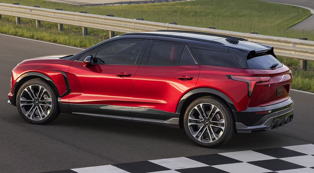 Side angle view of a red 2025 Chevy Blazer EV parked on a race track.