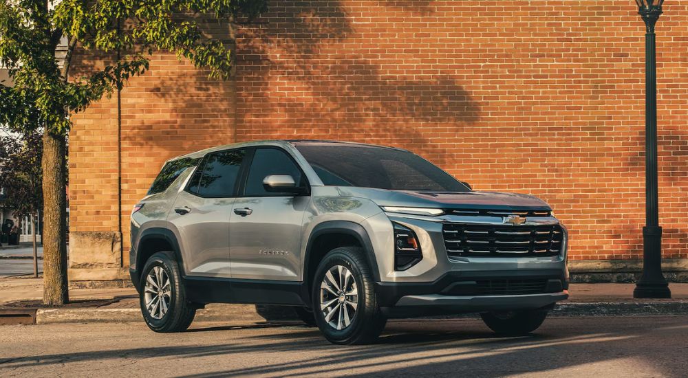 Grey 2026 Chevy Equinox parked in front of a brick building.