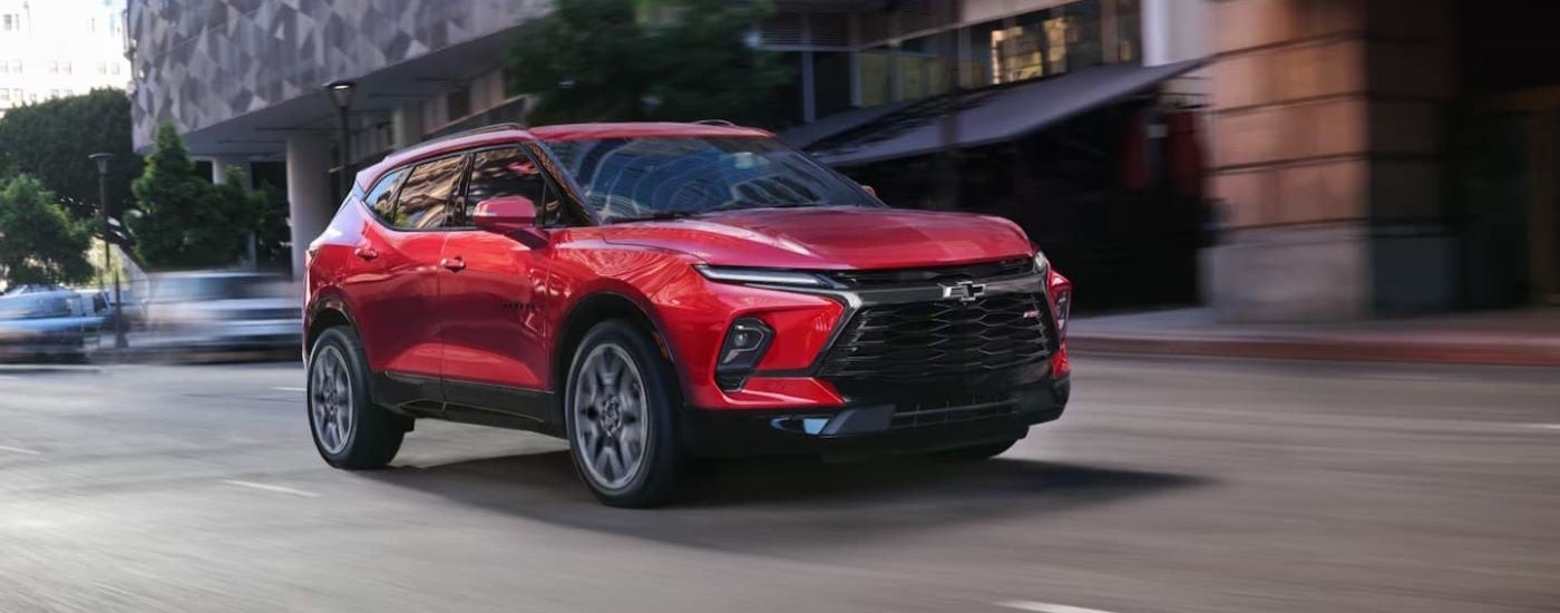 Red 2026 Chevy Blazer driving down a city street.