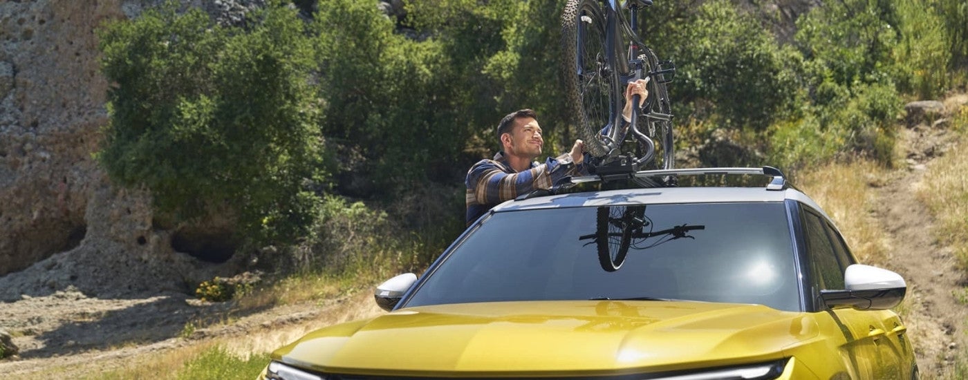 Person mounting bicycle to the roof of a yellow 2026 Chevy Trailblazer.