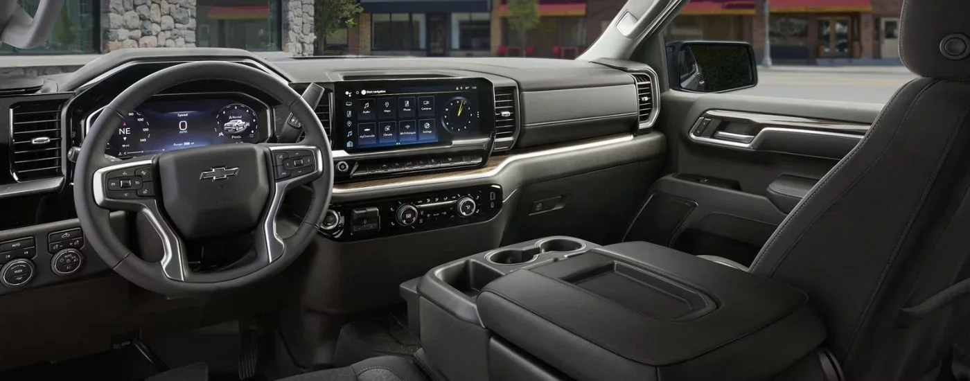 The front black interior of a 2026 Chevy Silverado 1500 showing the steering wheel and infotainment display.