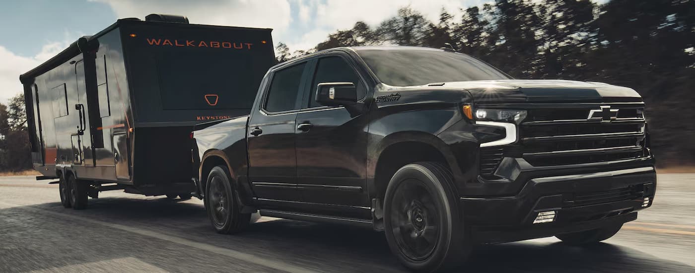 Black 2026 Chevy Silverado 1500 High Country towing a camper.