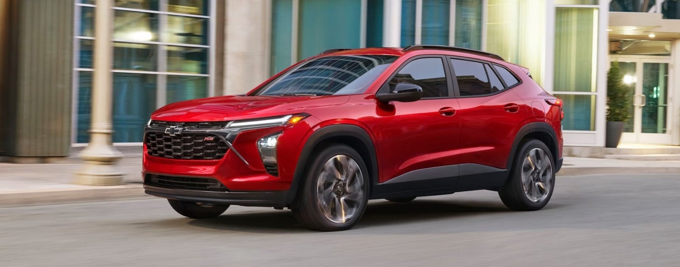 Red 2026 Chevy Trax driving down a city street.