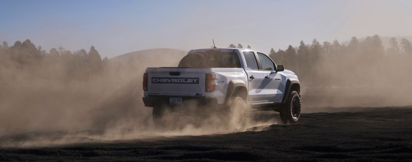 A white 2024 Chevy Colorado ZR2 Bison is shown from the rear kicking up dust.