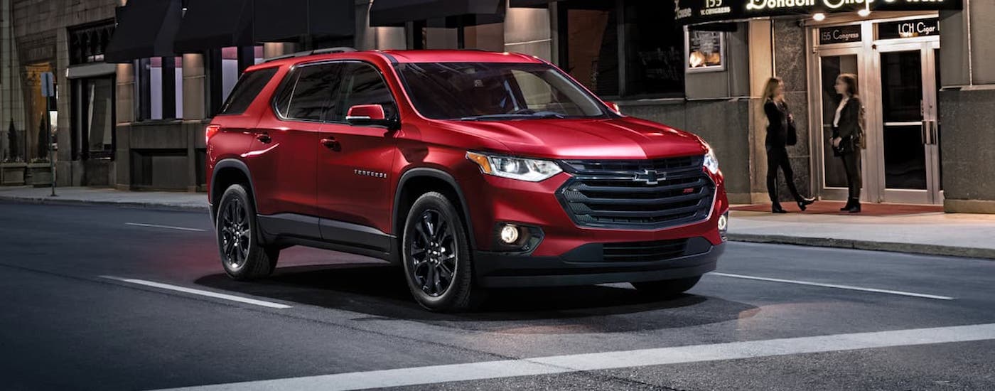 A red 2020 Chevy Traverse RS stopped at an intersection in a city.